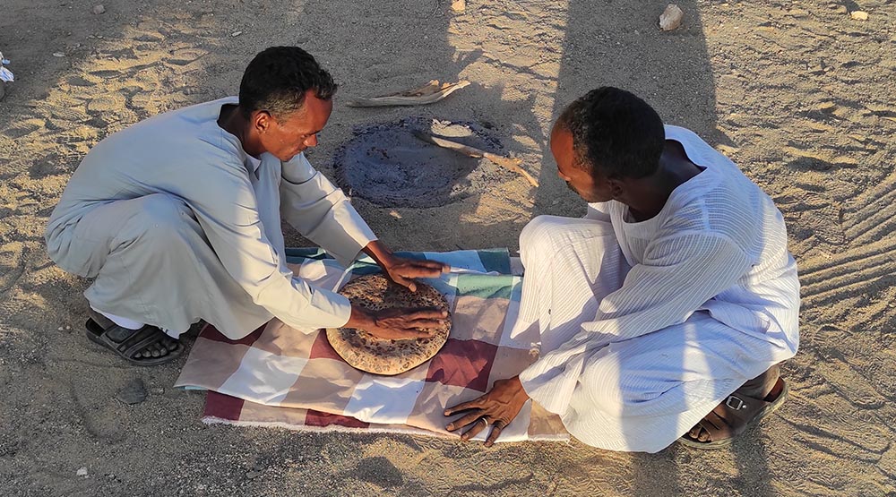 Einheimische beim Backen von Brot im heißen Sand. Foto: Michael Schabacker