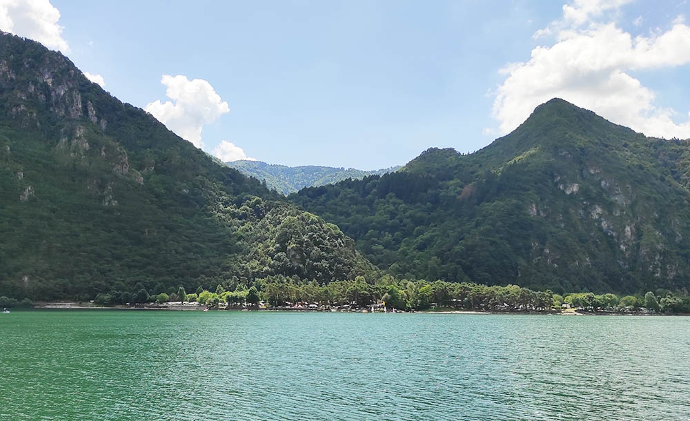 Vor idyllischer Kulisse des Monte Stino: in der Ferne Windsurfer vor einem Campingplatz. Foto: Michael Schabacker