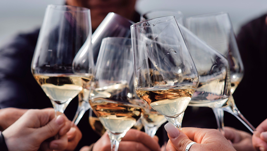 Anstoßen mit einem Glas Südtiroler Wein - und dann ein Fischgericht genießen. Foto: Südtirol Wein/Christine Rau