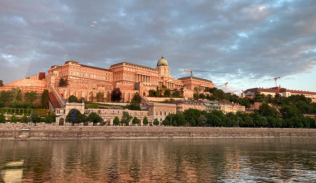 Die ungarische Hauptstadt schläft noch, als die Opal bei Sonnenaufgang Budapest erreicht. Zum Greifen nah das zuckerbäckerartige Parlamentsgebäude links und der orange-rosa leuchtende Buda-Schlossberg rechts. Foto: Uta Petersen