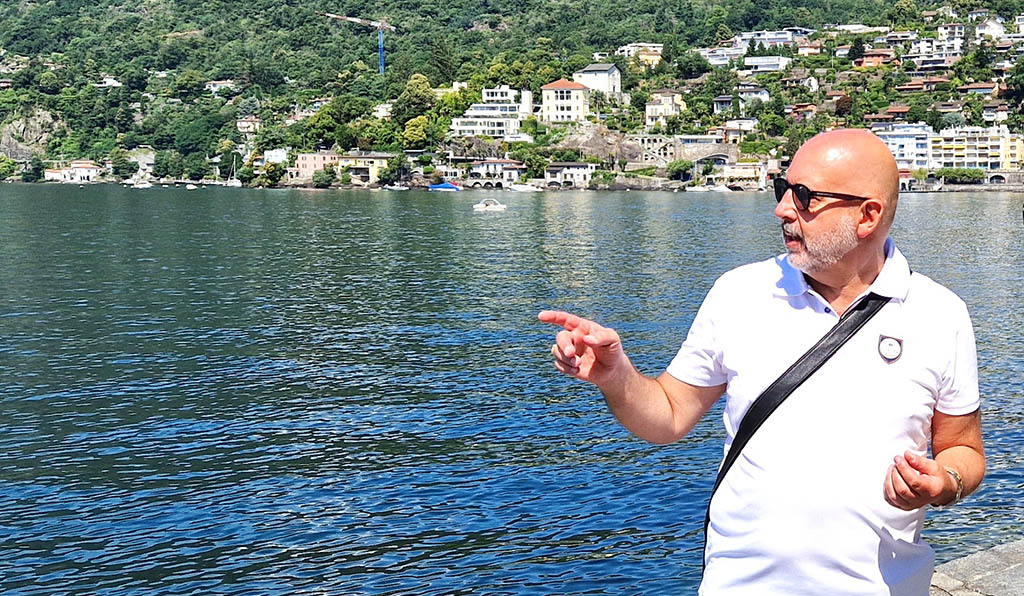 Claudio Caser vor dem Lago, umgeben von der malerischen Kulisse Asconas. Mit spürbarer Leidenschaft erzählt er von einem Ort, der mehr ist als nur Landschaft – ein Zuhause voller Geschichten und Begegnungen. Foto: Andreas Bienert