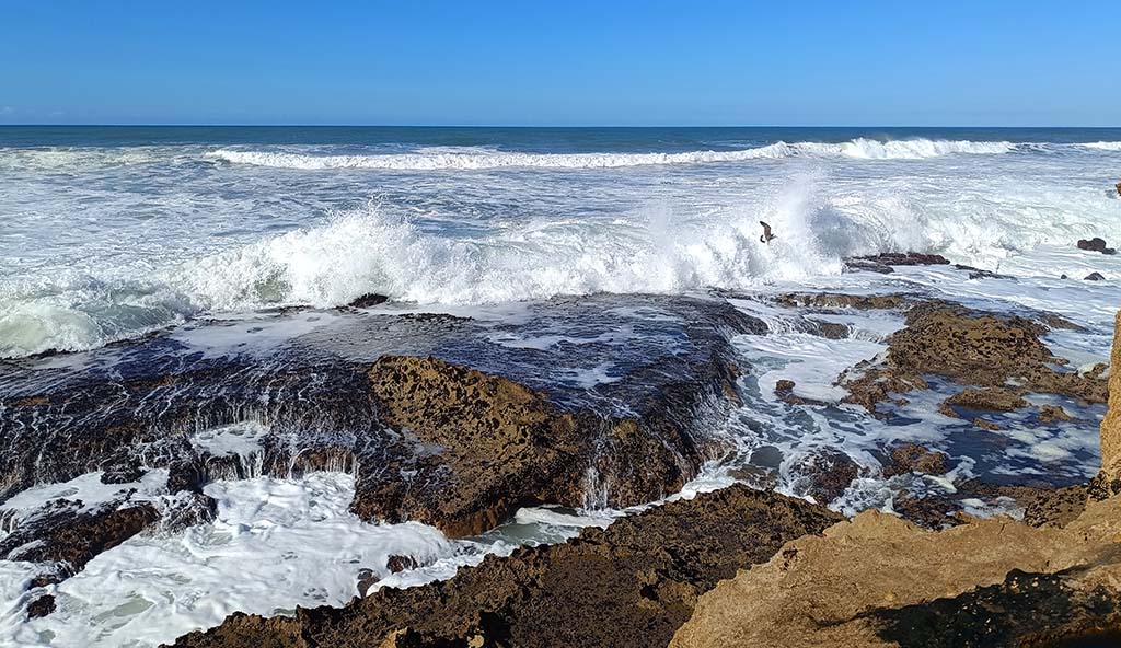 Ausblick von den Felsformationen auf die Gischt und die brechenden Wellen. Foto: Michael Schabacker